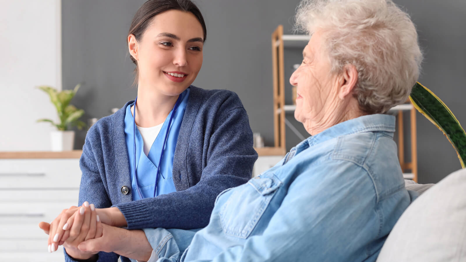 Nurse comforting an elderly woman while holding her hand.